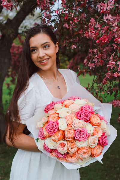 A large bouquet of 50 spring-toned roses in pink, peach, and white, lush and romantic