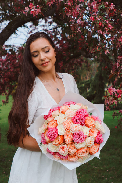 A large bouquet of 50 spring-toned roses in pink, peach, and white, lush and romantic