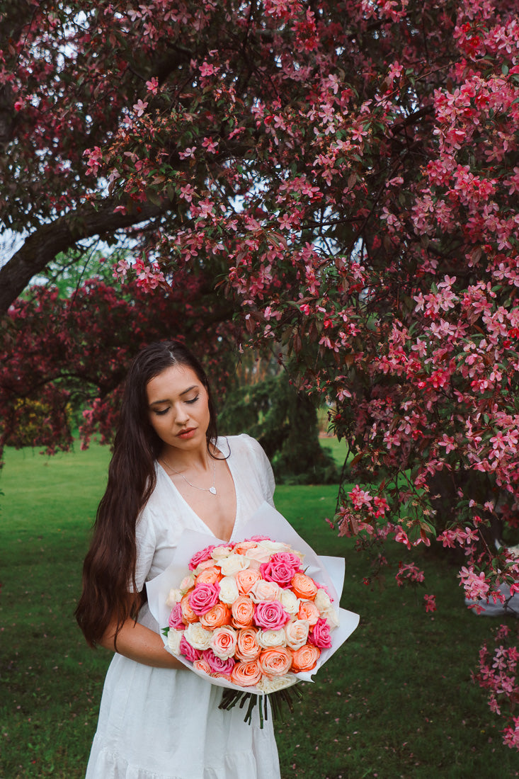 A large bouquet of 50 spring-toned roses in pink, peach, and white, lush and romantic