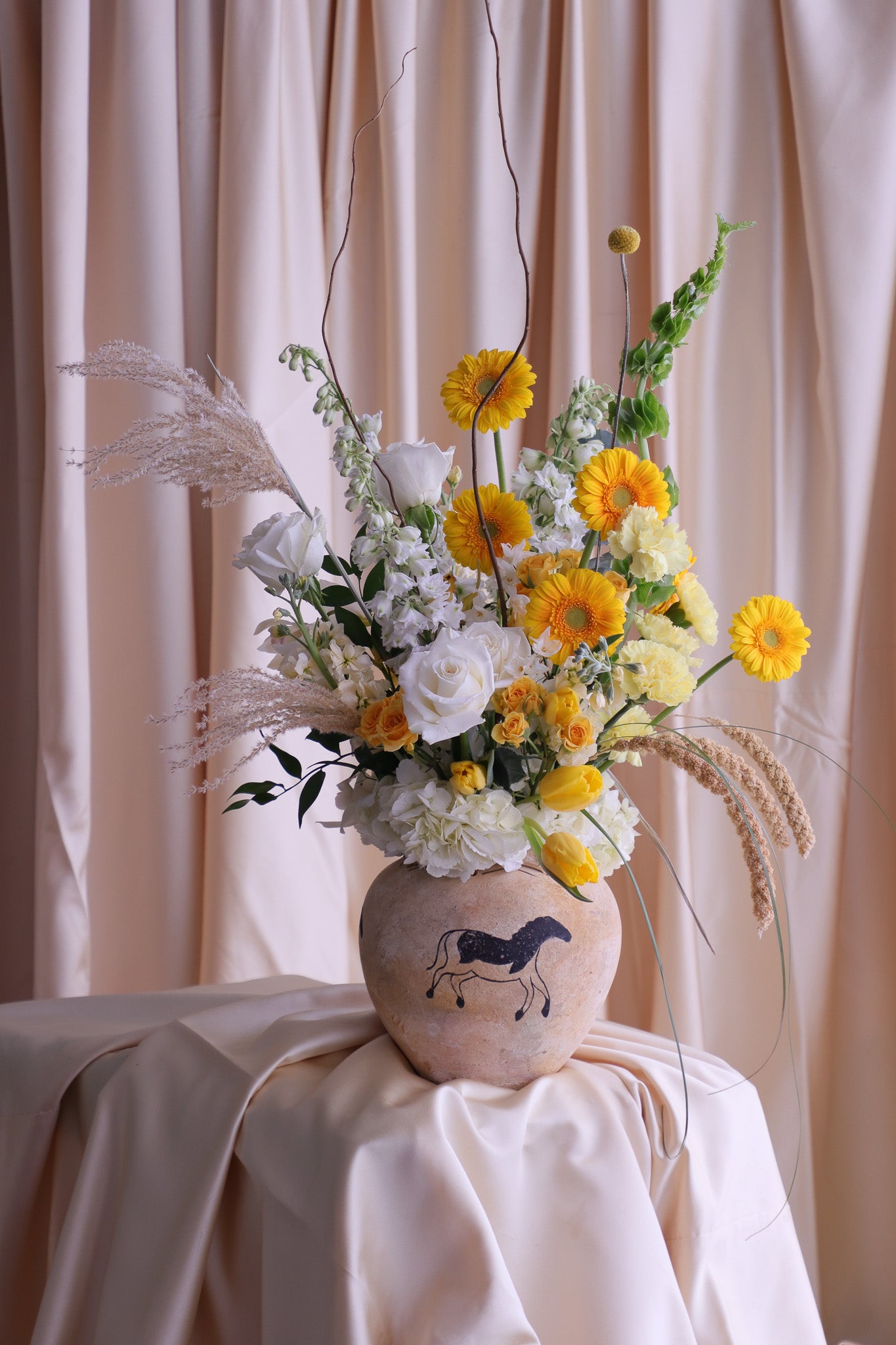 Floral yellow and white arrangement in a decorative vase on a table 