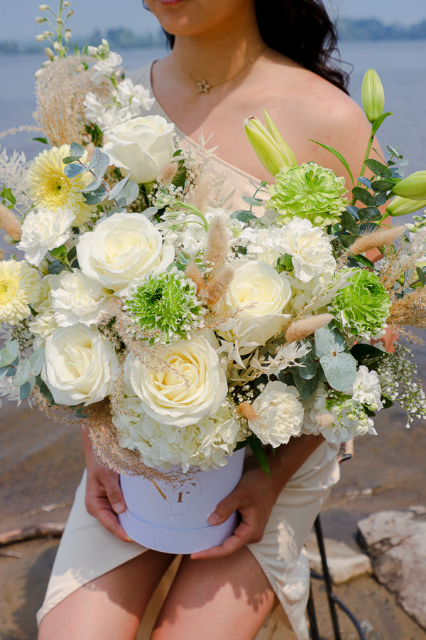  Elegant floral arrangement featuring white roses, lilies, and hydrangeas in a tall white box from an Ottawa florist.