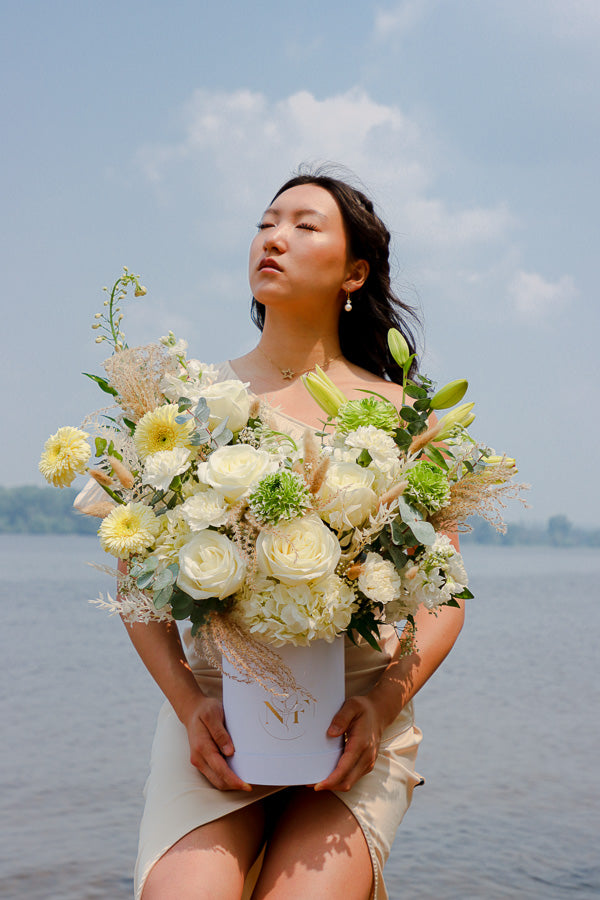  Elegant floral arrangement featuring white roses, lilies, and hydrangeas in a tall white box from an Ottawa florist.