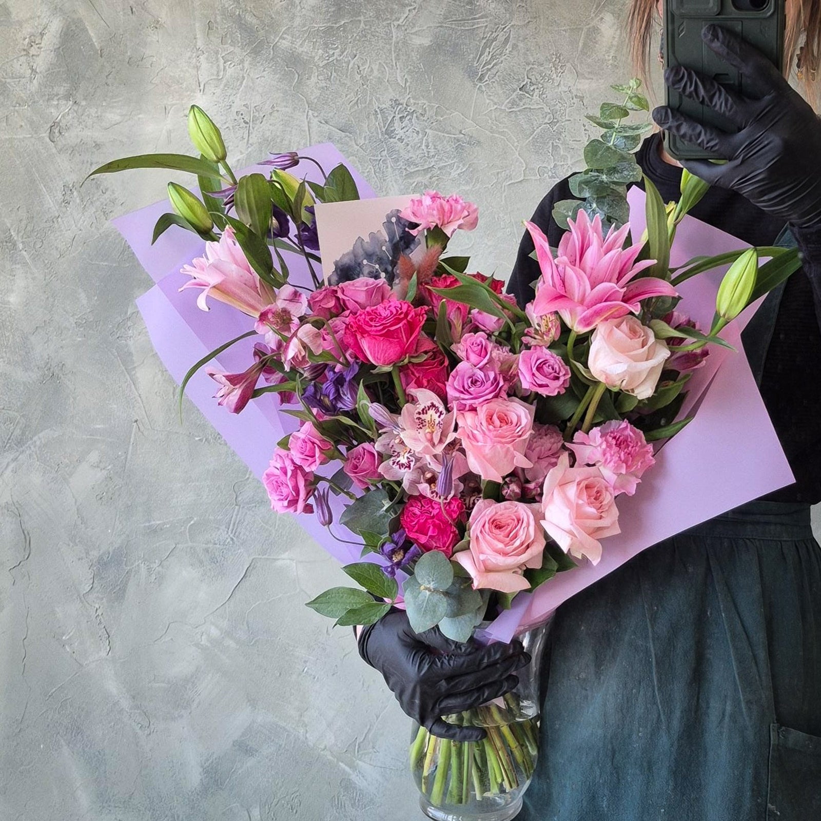 Person holding a bouquet of pink flowers with a gray background