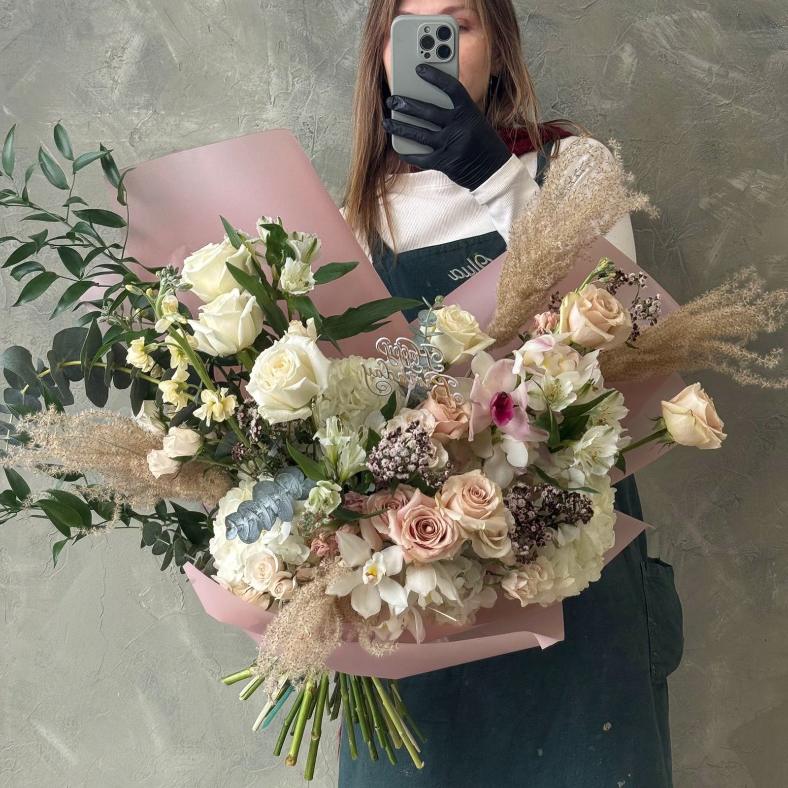 Person holding a bouquet of light color flowers with a neutral background