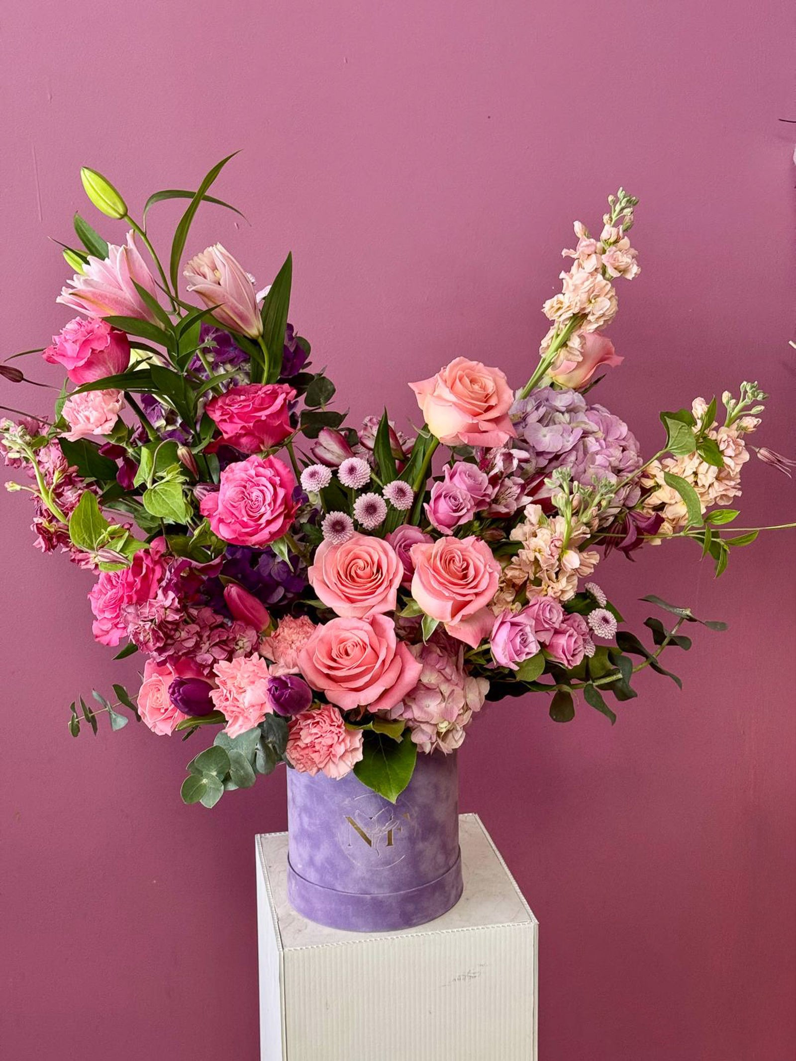 Box of pink and purple flowers in a purple box against a purple background