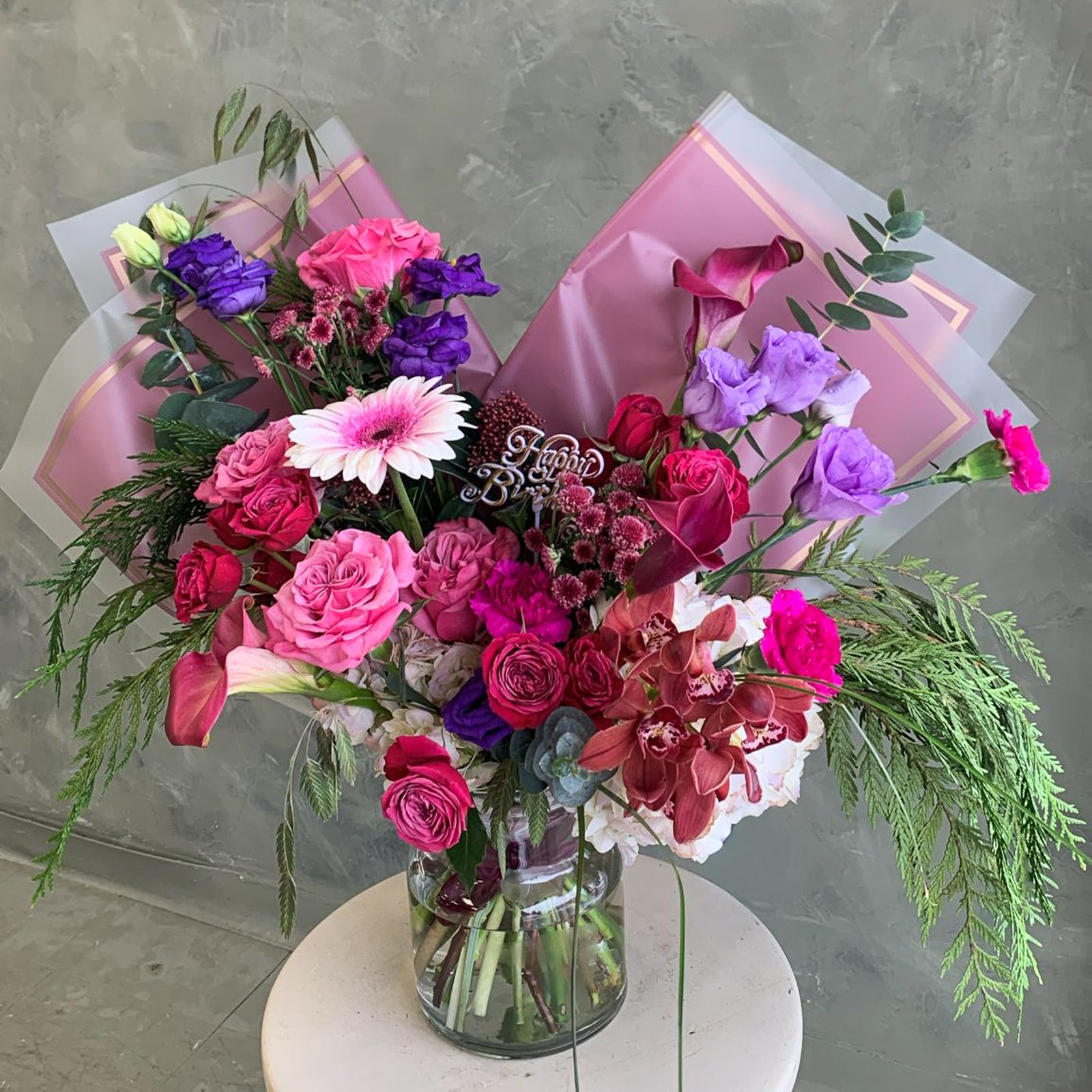 Bouquet of colorful flowers in a clear vase on a gray background