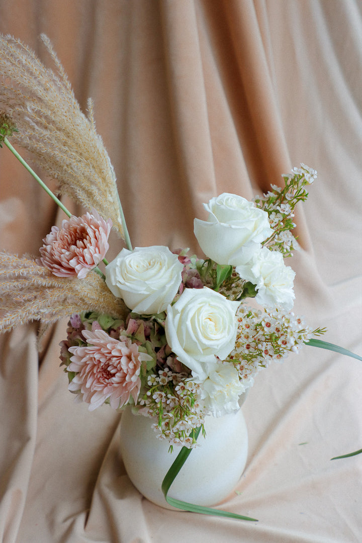 Silk &amp; Earth elegant ivory flower arrangement with white roses and cream florals in light ceramic vase.