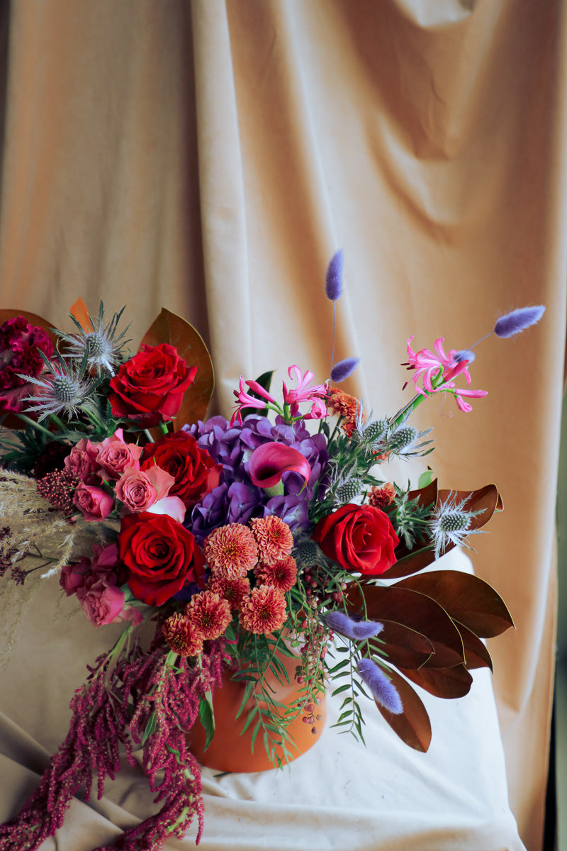 Warm and stylish fall arrangement with deep tones of reds, purples, browns and pinks, dry textures, and cozy seasonal flair