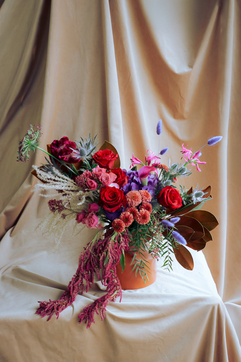 Warm and stylish fall arrangement with deep tones of reds, purples, browns and pinks, dry textures, and cozy seasonal flair