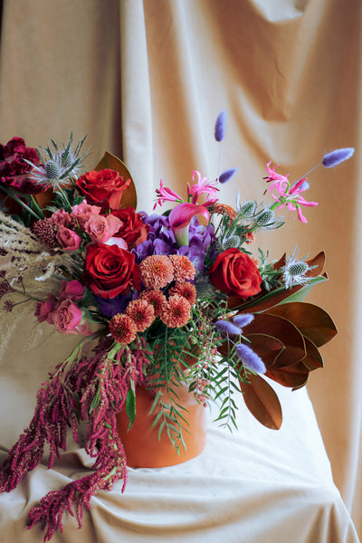 Warm and stylish fall arrangement with deep tones of reds, purples, browns and pinks, dry textures, and cozy seasonal flair
