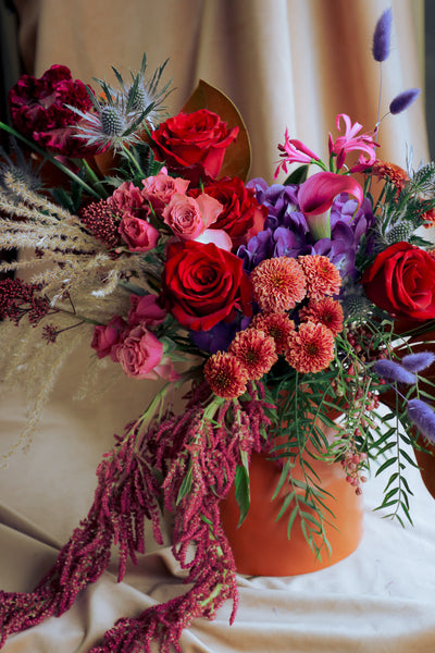 Warm and stylish fall arrangement with deep tones of reds, purples, browns and pinks, dry textures, and cozy seasonal flair