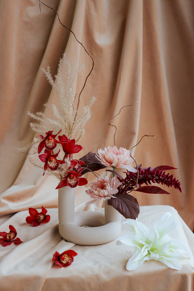 Compact autumn floral arrangement with orchids, amaranthus, willow branches, and dry details.
