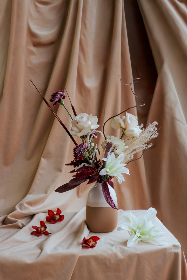 Wine &amp; Shadow fall flower arrangement in double-tone ceramic vase with dark burgundy and ivory blooms.