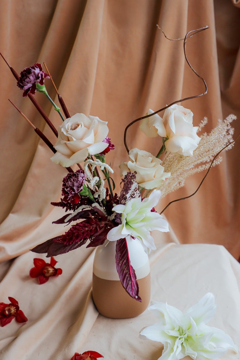 Wine &amp; Shadow fall flower arrangement in double-tone ceramic vase with dark burgundy and ivory blooms.
