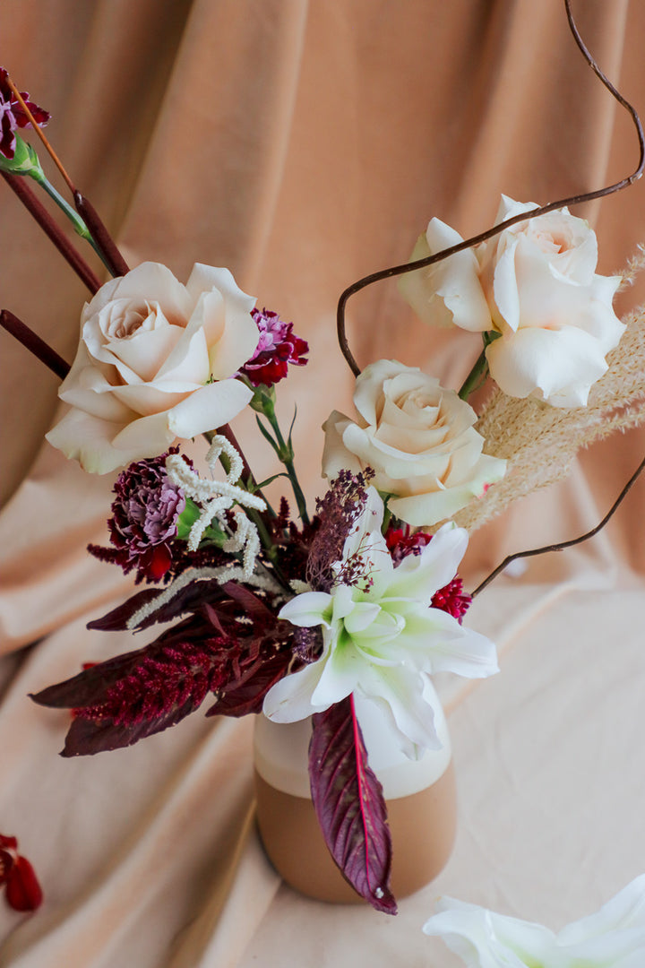 Wine &amp; Shadow fall flower arrangement in double-tone ceramic vase with dark burgundy and ivory blooms.
