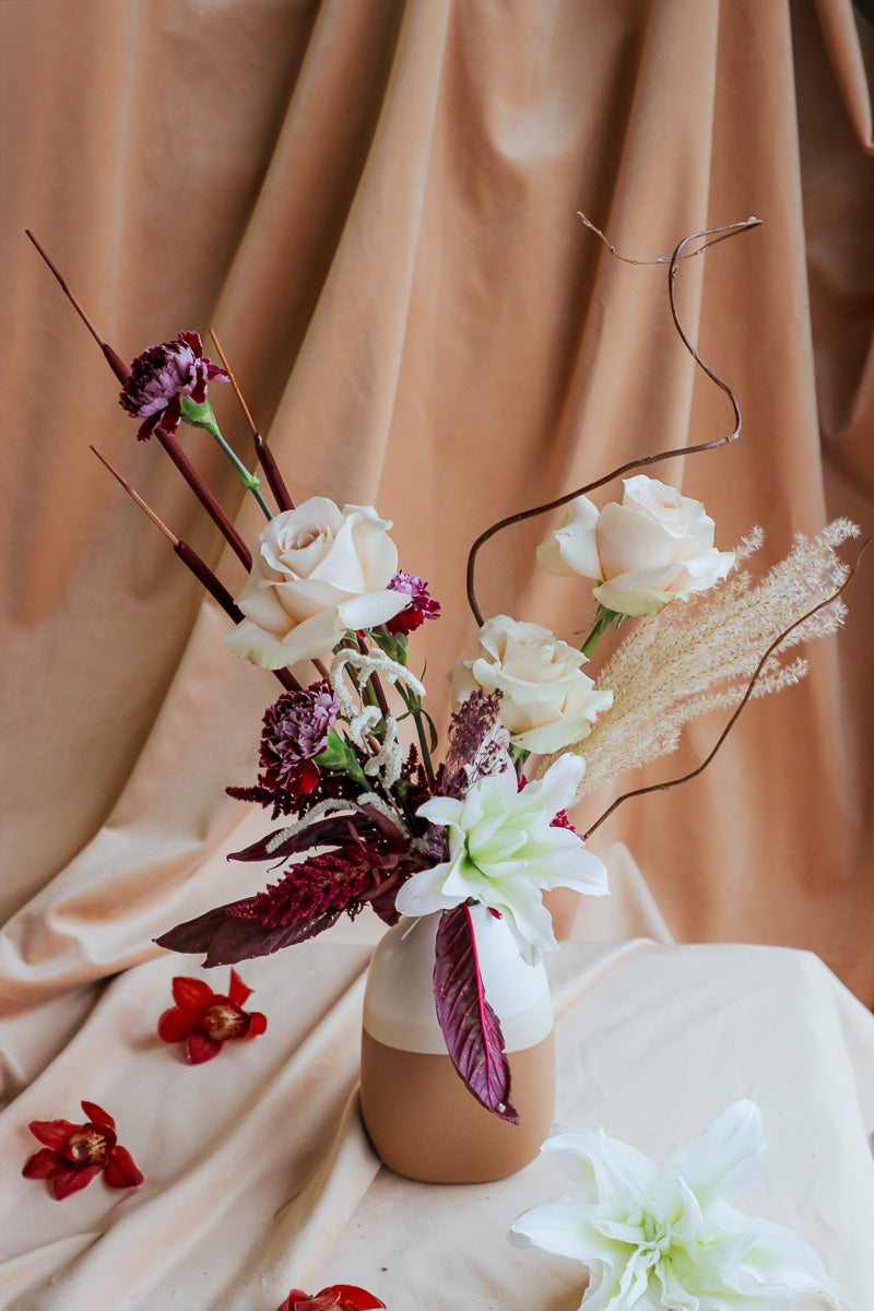 Wine &amp; Shadow fall flower arrangement in double-tone ceramic vase with dark burgundy and ivory blooms.