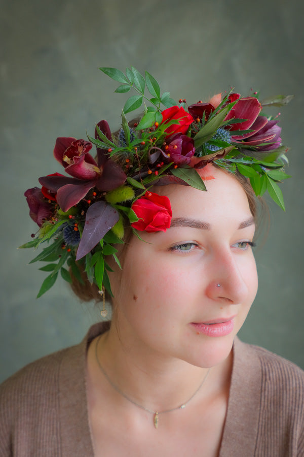 Woman wearing a floral headpiece, flower crown with red and green flowers 