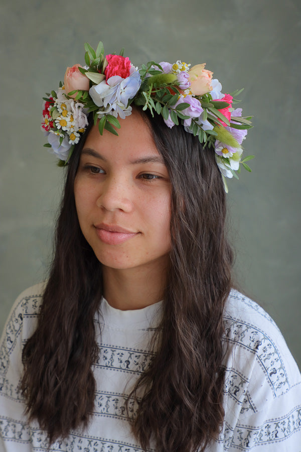 Woman wearing a bright blue and pink floral crown with wildflowers