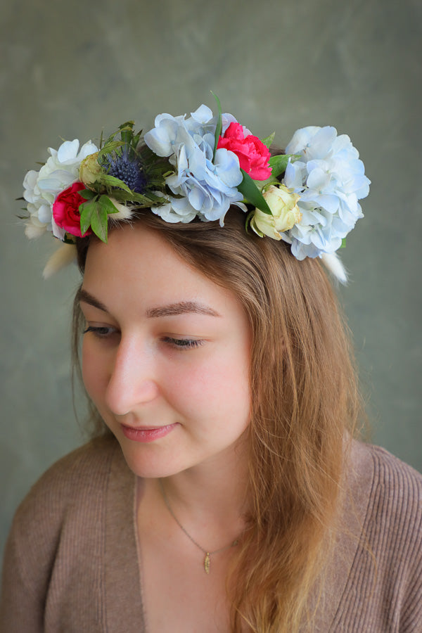 Woman wearing a floral headband with white, pink, and green flowers 
