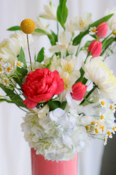 "Good Mood" arrangement featuring vibrant coral peonies, sunny yellow accents, and lush garden blooms in a stylish coral polka-dot vase.