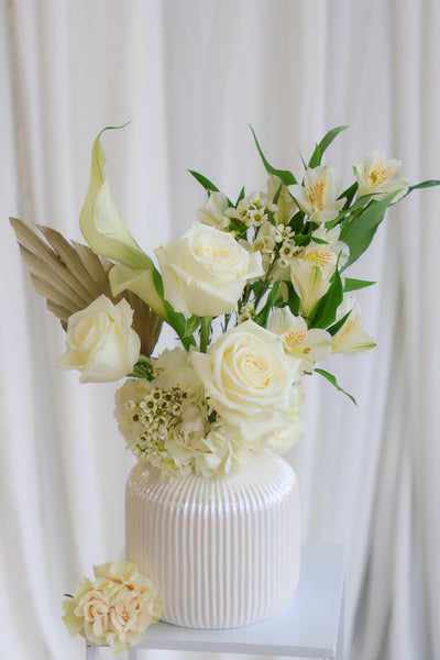Elegant "Mom's Hug" flower arrangement featuring white and cream roses, hydrangeas, and calla lilies in a stylish cream vase—perfect as Mother's Day flowers or for any heartfelt occasion.