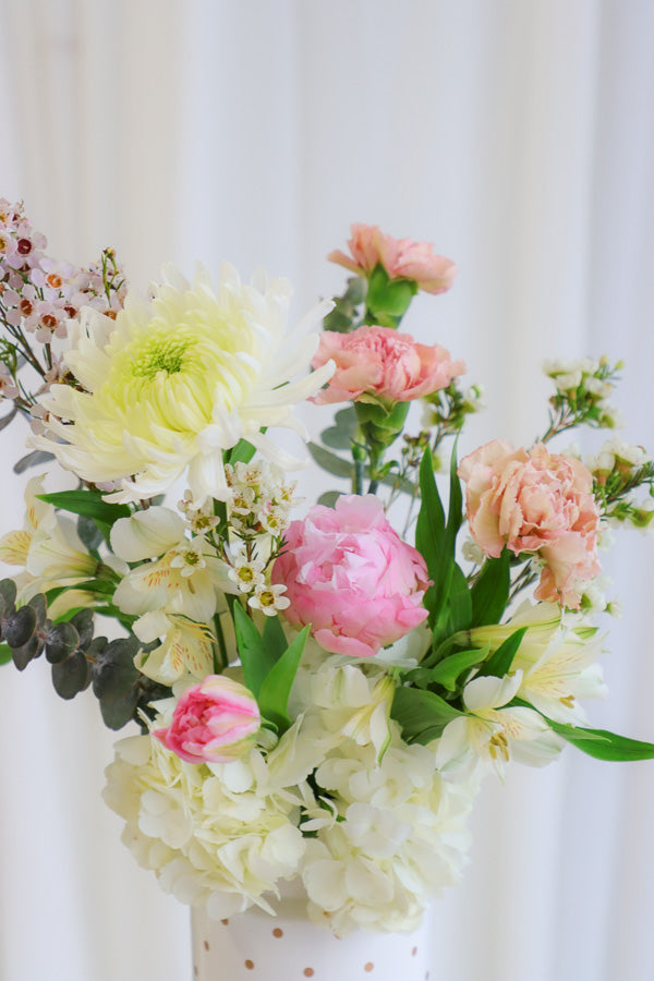 Cheerful "Happy Vibes" arrangement with pink peonies, white hydrangeas, and other gorgeous pink and white flowers in a playful white polka dot vase.