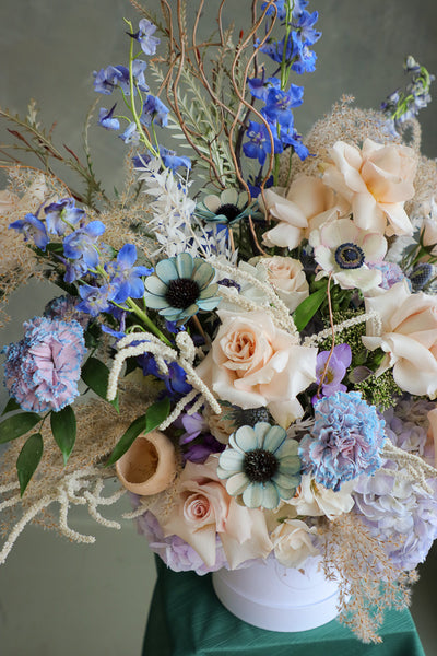 Coastal Dream luxurious floral arrangement with shades of blue, cream, and white, accented by branches and dry decor by Ottawa flower shop.