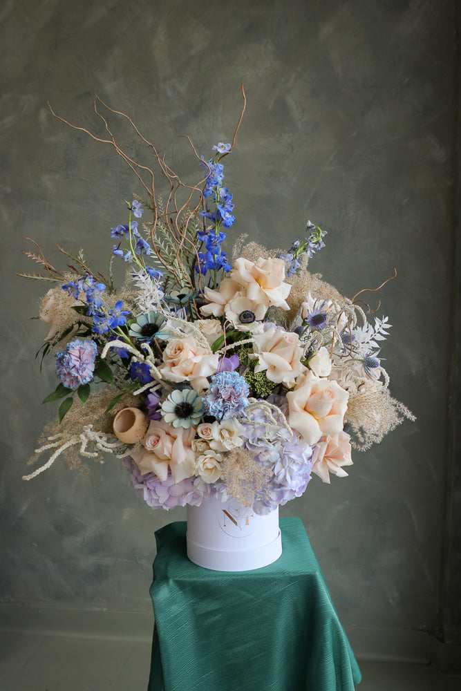 Coastal Dream luxurious floral arrangement with shades of blue, cream, and white, accented by branches and dry decor by Ottawa flower shop.