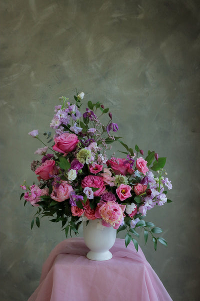 flower centerpiece with shades of purple and pink flowers in an elegant white ceramic vase by Ottawa florist.