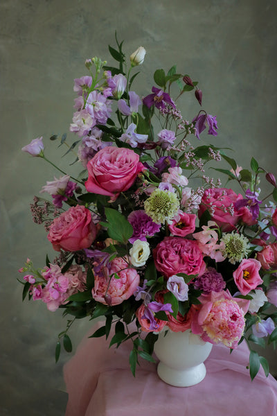 flower centerpiece with shades of purple and pink flowers in an elegant white ceramic vase by Ottawa florist.