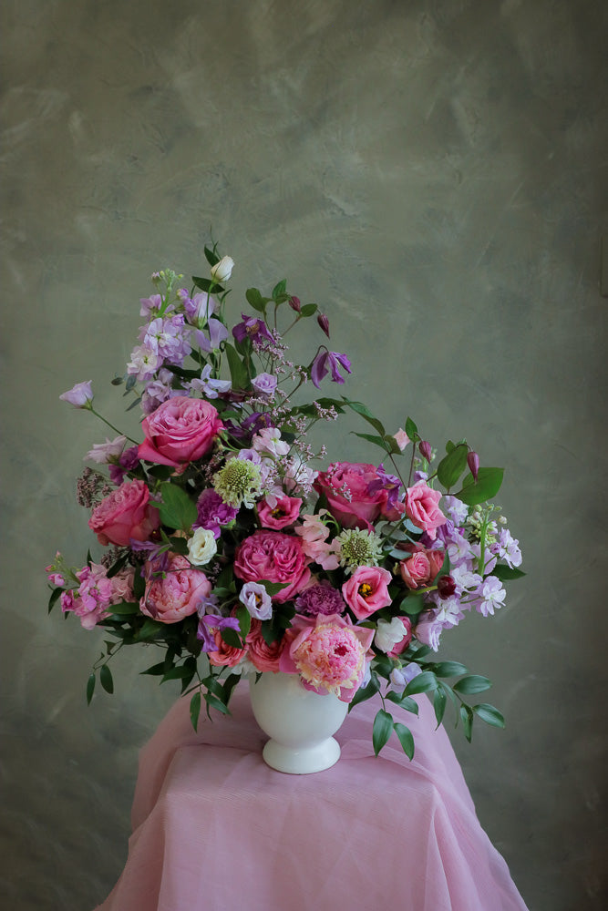 flower centerpiece with shades of purple and pink flowers in an elegant white ceramic vase by Ottawa florist.