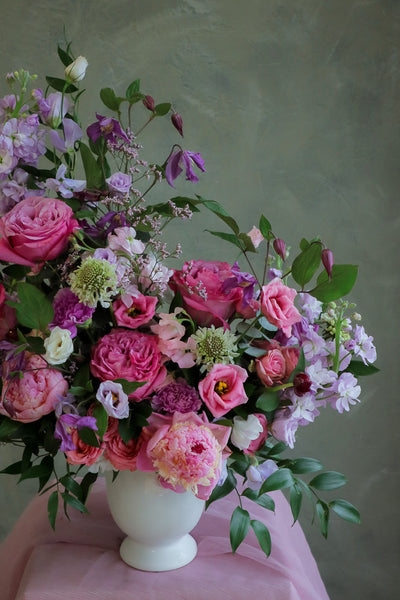 flower centerpiece with shades of purple and pink flowers in an elegant white ceramic vase by Ottawa florist.