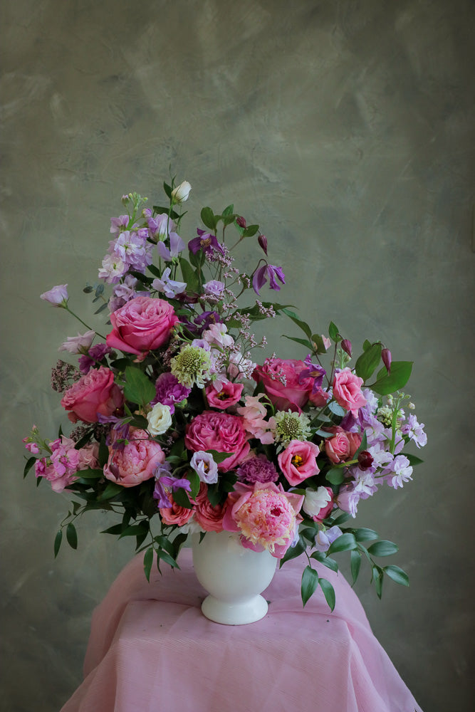 flower centerpiece with shades of purple and pink flowers in an elegant white ceramic vase by Ottawa florist.