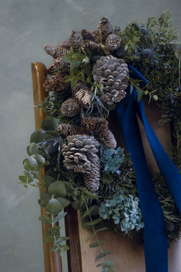 Frosted Elegance wreath with white accents, eucalyptus, silver pinecones, thistle, and a blue velvet ribbon by Ottawa florist.