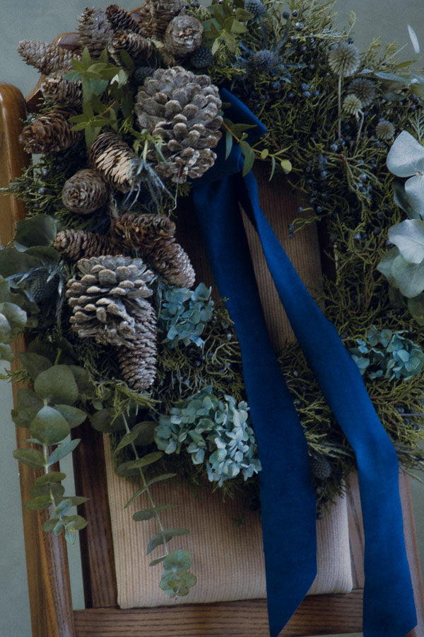 Frosted Elegance wreath with white accents, eucalyptus, silver pinecones, thistle, and a blue velvet ribbon by Ottawa florist.