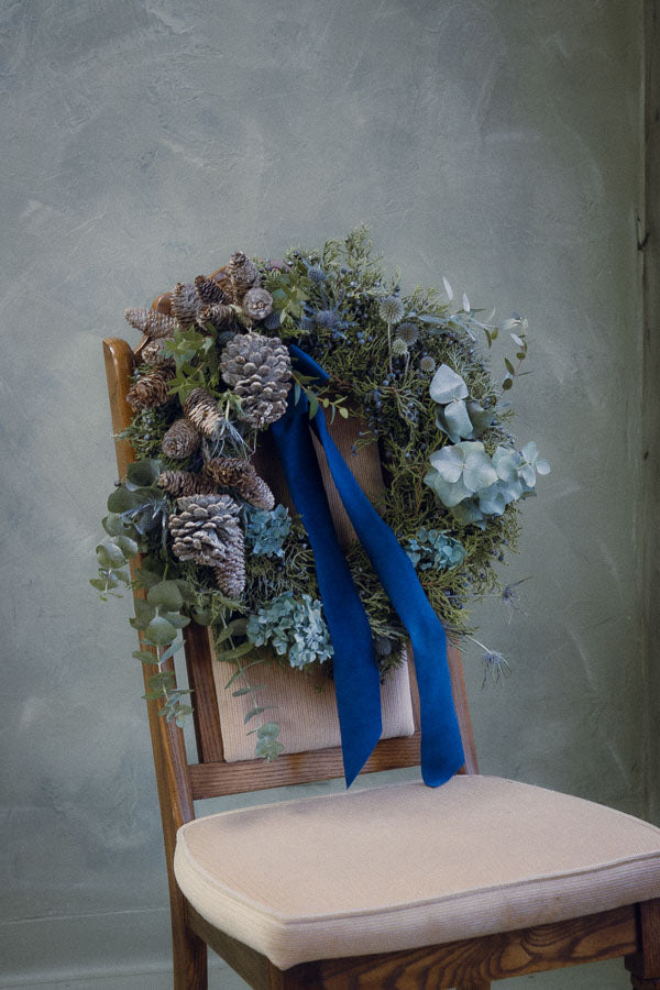 Frosted Elegance wreath with white accents, eucalyptus, silver pinecones, thistle, and a blue velvet ribbon by Ottawa florist.