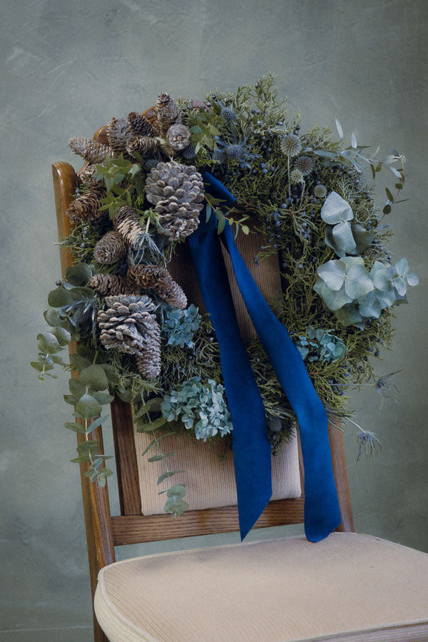 Frosted Elegance wreath with white accents, eucalyptus, silver pinecones, thistle, and a blue velvet ribbon by Ottawa florist.