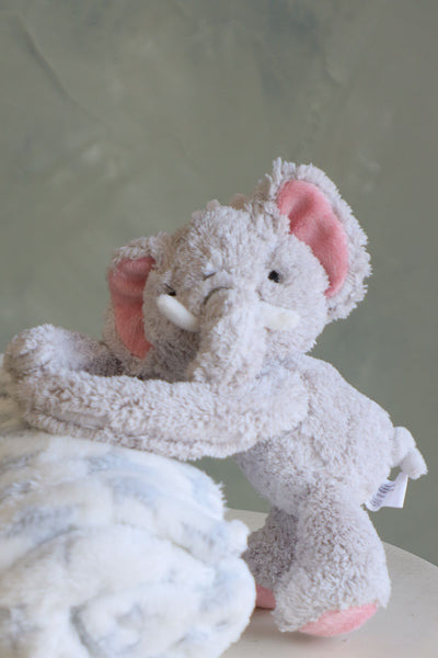 Fluffy gray elephant plush hugging a white fleece blanket with gray stars