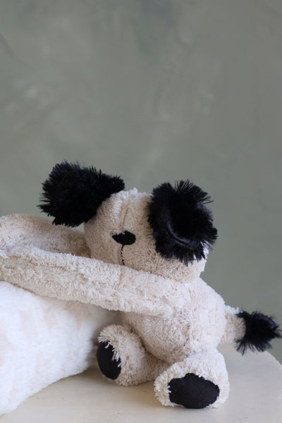 Cream-colored puppy plush holding a white blanket with pale beige stars