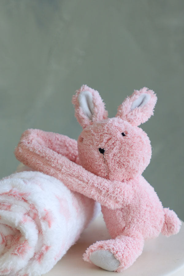 Soft pink bunny plush holding a white fleece blanket with pink stars