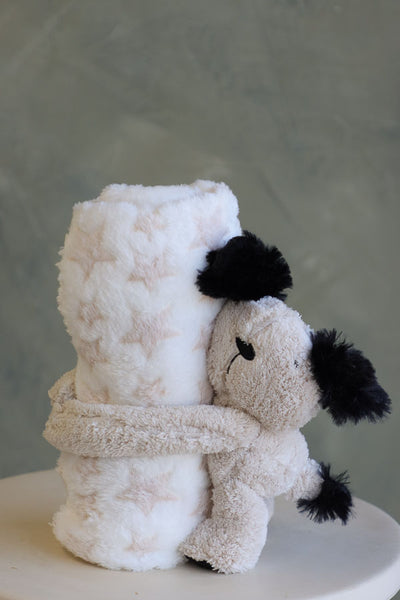 Cream-colored puppy plush holding a white blanket with pale beige stars
