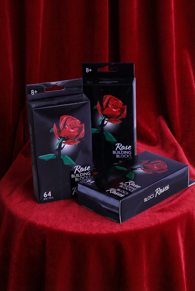 3 Red rose building block kits displayed in a black boxes, surrounded by red roses on a velvet background for Valentine’s Day