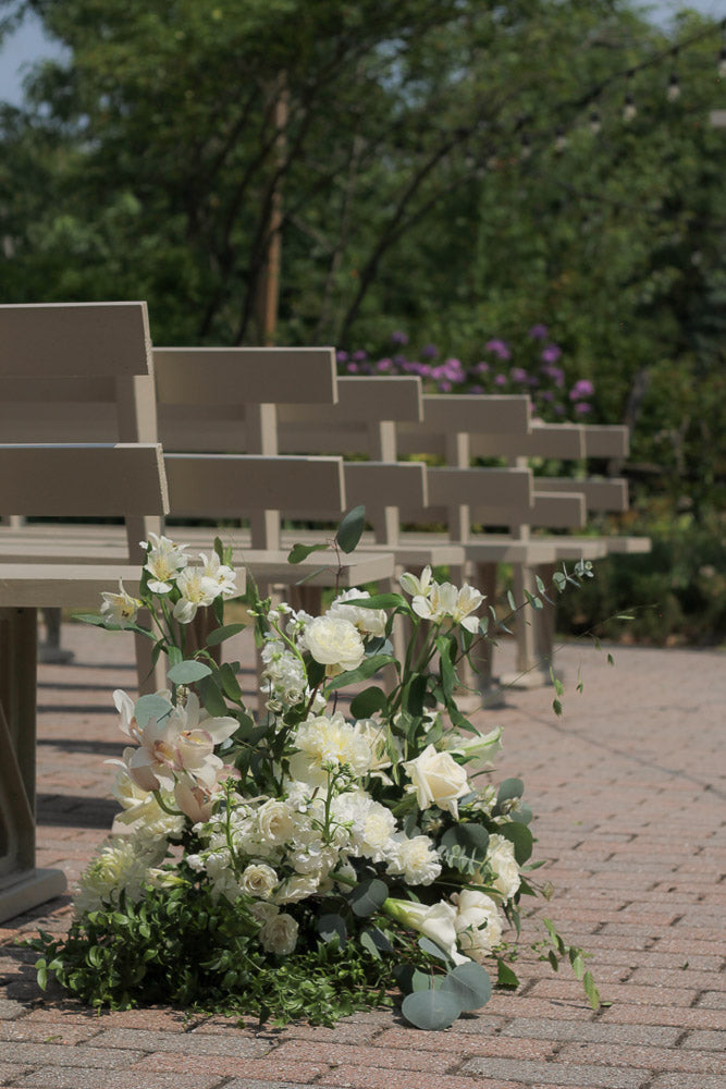 Decorative floral arrangement in front of rows of chairs with a blurred natural background