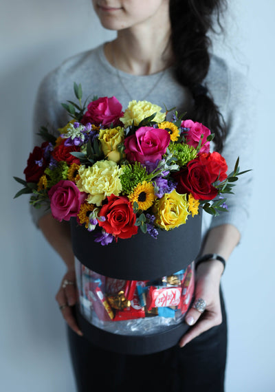 Girl holding flowers in a box with chocolates