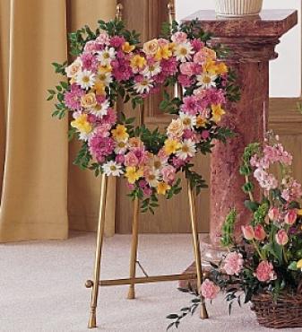 flowers in an open heart shape; pink  white and orange funeral  flower heart; standing flower spray in shape of a heart